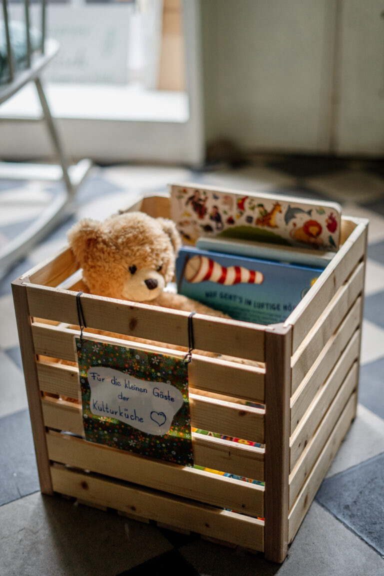 Bild von einem Holzkorb, in dem ein Kuscheltier-Bär sitzt.