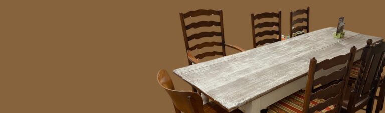 Grauer langer Tisch mit sechs Holzstühlen.