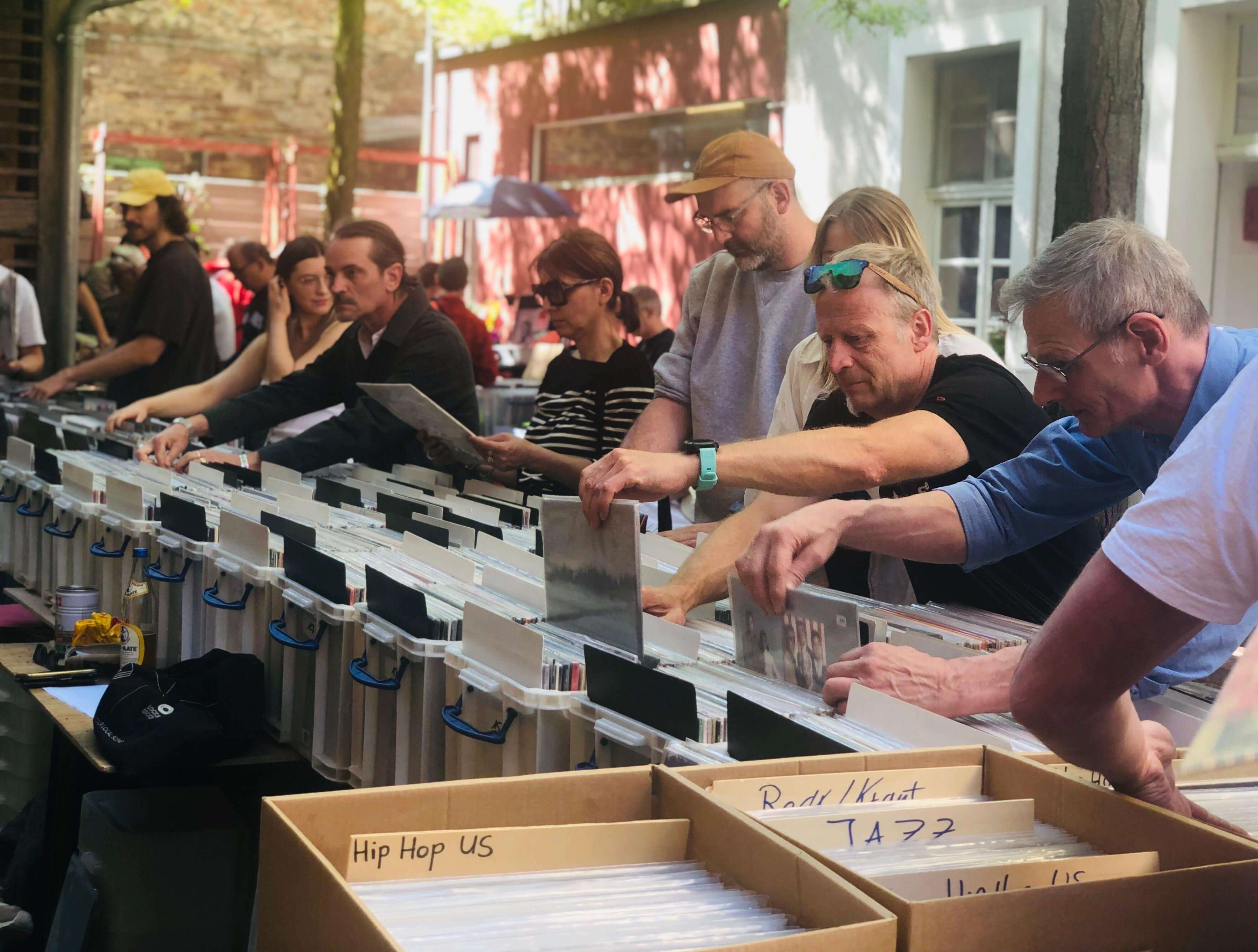 Verschiedene Menschen wühlen sich im Innenhof der Kulturküche durch Platten beim Vinyl-Flohmarkt.