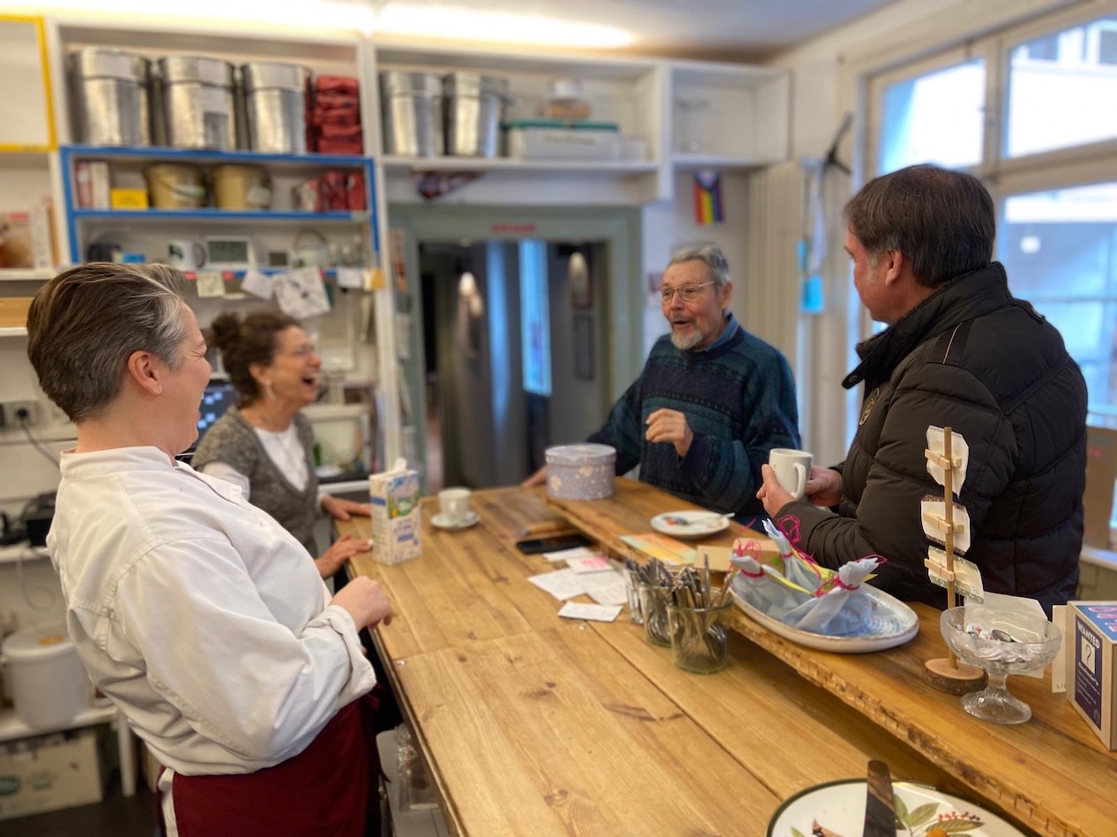 An der Theke der Kulturküche stehen vier Menschen, die sich miteinander unterhaltener und lachen.
