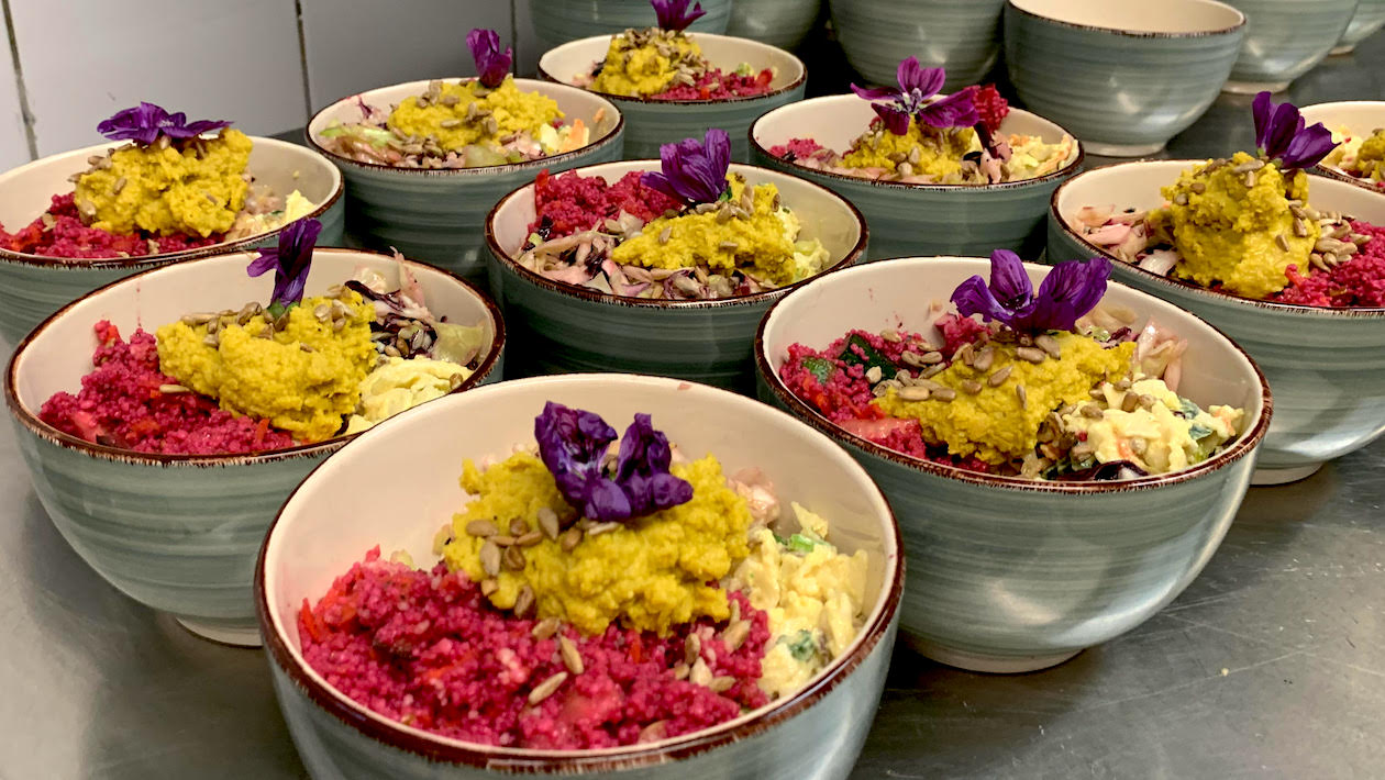 Neun Suppenschüsseln mit einem bunten Potpourri an Zutaten. Oben garniert mit einer Lianen Blüte.