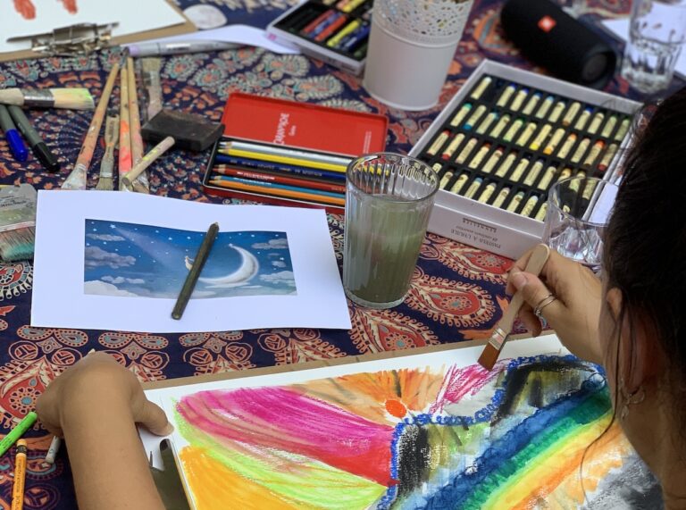 Farben, Pinsel und Bilde liegen auf einem Tisch.