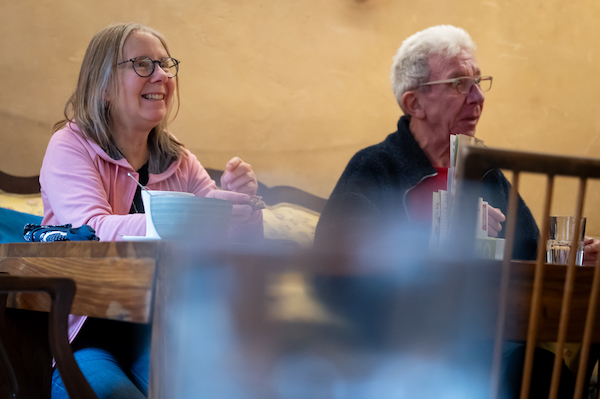 Zwei ältere Menschen sitzen an einem Holztisch.