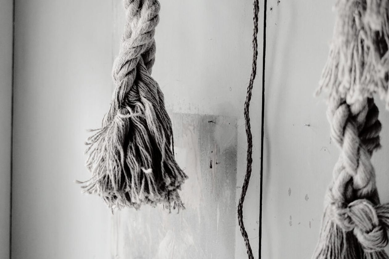 Schwarz-weiß Foto. Seile hängen von der Decke.